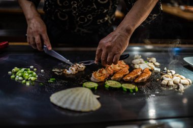 Teppanyaki, geleneksel bir Japon restoranında Japon Teppan Şovu. Aşçının elleri. Japon aşçı sıcak masada et, balık, pirinç ve sebze hazırlar.