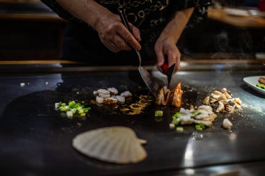 Teppanyaki, geleneksel bir Japon restoranında Japon Teppan Şovu. Aşçının elleri. Japon aşçı sıcak masada et, balık, pirinç ve sebze hazırlar.