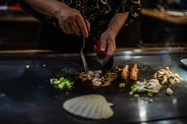 Teppanyaki, geleneksel bir Japon restoranında Japon Teppan Şovu. Aşçının elleri. Japon aşçı sıcak masada et, balık, pirinç ve sebze hazırlar.