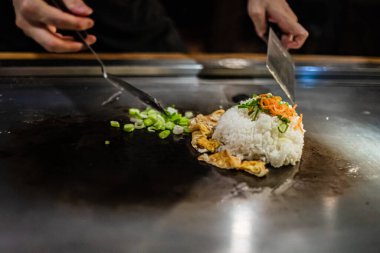 Teppanyaki, geleneksel bir Japon restoranında Japon Teppan Şovu. Aşçının elleri. Japon aşçı sıcak masada et, balık, pirinç ve sebze hazırlar.
