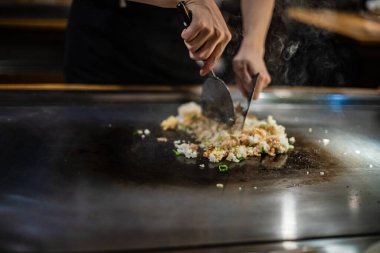 Teppanyaki, geleneksel bir Japon restoranında Japon Teppan Şovu. Aşçının elleri. Japon aşçı sıcak masada et, balık, pirinç ve sebze hazırlar.