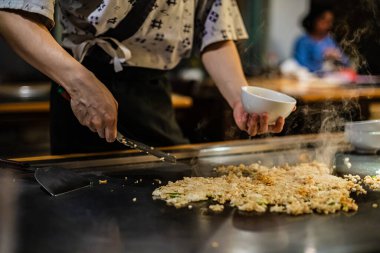 Teppanyaki, geleneksel bir Japon restoranında Japon Teppan Şovu. Aşçının elleri. Japon aşçı sıcak masada et, balık, pirinç ve sebze hazırlar.