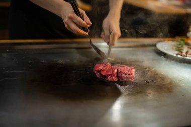 Teppanyaki, geleneksel bir Japon restoranında Japon Teppan Şovu. Aşçının elleri. Japon aşçı sıcak masada et, balık, pirinç ve sebze hazırlar.