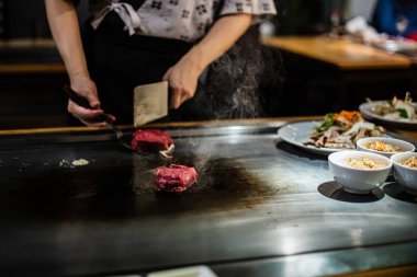 Teppanyaki, geleneksel bir Japon restoranında Japon Teppan Şovu. Aşçının elleri. Japon aşçı sıcak masada et, balık, pirinç ve sebze hazırlar.