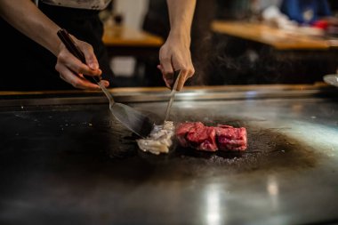 Teppanyaki, geleneksel bir Japon restoranında Japon Teppan Şovu. Aşçının elleri. Japon aşçı sıcak masada et, balık, pirinç ve sebze hazırlar.