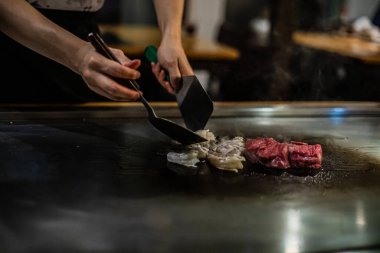 Teppanyaki, geleneksel bir Japon restoranında Japon Teppan Şovu. Aşçının elleri. Japon aşçı sıcak masada et, balık, pirinç ve sebze hazırlar.