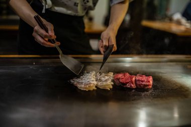 Teppanyaki, geleneksel bir Japon restoranında Japon Teppan Şovu. Aşçının elleri. Japon aşçı sıcak masada et, balık, pirinç ve sebze hazırlar.