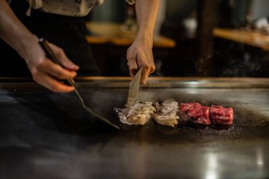 Teppanyaki, geleneksel bir Japon restoranında Japon Teppan Şovu. Aşçının elleri. Japon aşçı sıcak masada et, balık, pirinç ve sebze hazırlar.