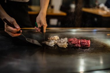 Teppanyaki, geleneksel bir Japon restoranında Japon Teppan Şovu. Aşçının elleri. Japon aşçı sıcak masada et, balık, pirinç ve sebze hazırlar.