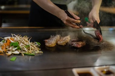 Teppanyaki, geleneksel bir Japon restoranında Japon Teppan Şovu. Aşçının elleri. Japon aşçı sıcak masada et, balık, pirinç ve sebze hazırlar.