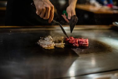 Teppanyaki, geleneksel bir Japon restoranında Japon Teppan Şovu. Aşçının elleri. Japon aşçı sıcak masada et, balık, pirinç ve sebze hazırlar.
