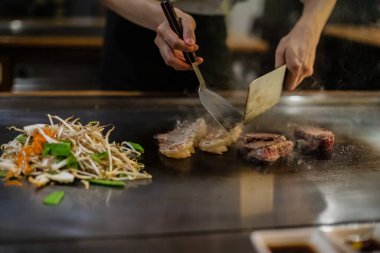 Teppanyaki, geleneksel bir Japon restoranında Japon Teppan Şovu. Aşçının elleri. Japon aşçı sıcak masada et, balık, pirinç ve sebze hazırlar.
