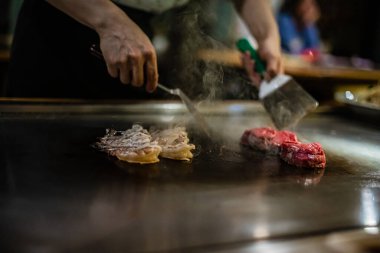 Teppanyaki, geleneksel bir Japon restoranında Japon Teppan Şovu. Aşçının elleri. Japon aşçı sıcak masada et, balık, pirinç ve sebze hazırlar.