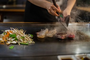 Teppanyaki, geleneksel bir Japon restoranında Japon Teppan Şovu. Aşçının elleri. Japon aşçı sıcak masada et, balık, pirinç ve sebze hazırlar.