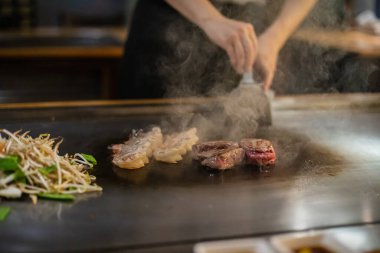 Teppanyaki, geleneksel bir Japon restoranında Japon Teppan Şovu. Aşçının elleri. Japon aşçı sıcak masada et, balık, pirinç ve sebze hazırlar.