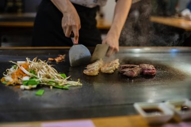 Teppanyaki, geleneksel bir Japon restoranında Japon Teppan Şovu. Aşçının elleri. Japon aşçı sıcak masada et, balık, pirinç ve sebze hazırlar.