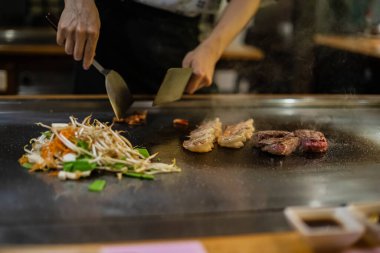 Teppanyaki, geleneksel bir Japon restoranında Japon Teppan Şovu. Aşçının elleri. Japon aşçı sıcak masada et, balık, pirinç ve sebze hazırlar.