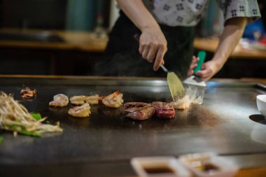 Teppanyaki, geleneksel bir Japon restoranında Japon Teppan Şovu. Aşçının elleri. Japon aşçı sıcak masada et, balık, pirinç ve sebze hazırlar.