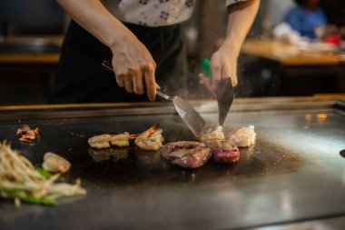 Teppanyaki, geleneksel bir Japon restoranında Japon Teppan Şovu. Aşçının elleri. Japon aşçı sıcak masada et, balık, pirinç ve sebze hazırlar.