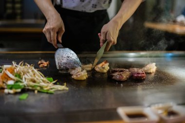 Teppanyaki, geleneksel bir Japon restoranında Japon Teppan Şovu. Aşçının elleri. Japon aşçı sıcak masada et, balık, pirinç ve sebze hazırlar.