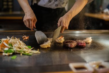 Teppanyaki, geleneksel bir Japon restoranında Japon Teppan Şovu. Aşçının elleri. Japon aşçı sıcak masada et, balık, pirinç ve sebze hazırlar.