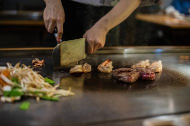 Teppanyaki, geleneksel bir Japon restoranında Japon Teppan Şovu. Aşçının elleri. Japon aşçı sıcak masada et, balık, pirinç ve sebze hazırlar.