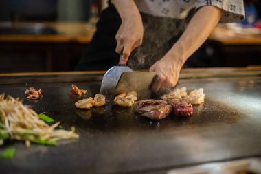 Teppanyaki, geleneksel bir Japon restoranında Japon Teppan Şovu. Aşçının elleri. Japon aşçı sıcak masada et, balık, pirinç ve sebze hazırlar.