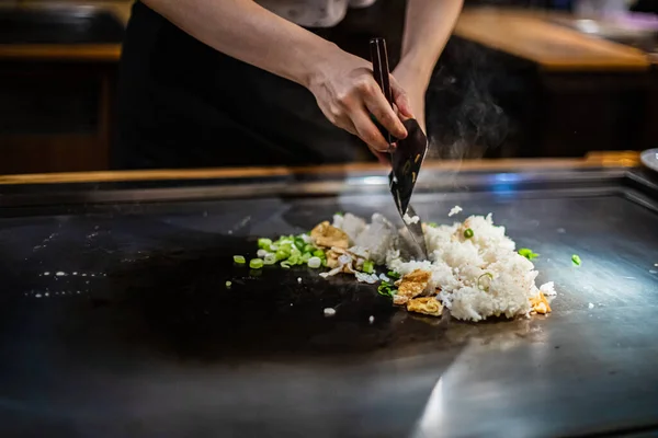 Teppanyaki, Japanese Cooking teppan show at a traditional Japanese restaurant. hands of the cook. Japanese cook prepares meat, fish, rice, vegetables on the hot table