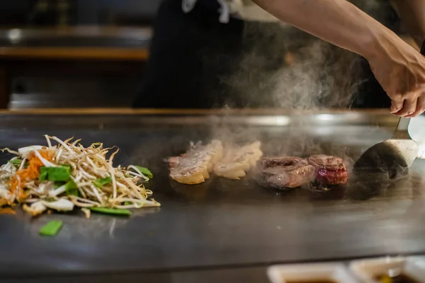 鉄板焼き 日本の伝統料理店での鉄板焼きショー 料理人の手だ 日本の料理人は熱いテーブルの上に肉 野菜を準備します — ストック写真