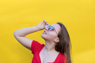 Çok mutlu bir bayanın kırmızı elbise giyip boş bir yere baktığı yakın plan bir fotoğraf. izole edilmiş sarı arkaplan. Genç duygusal kız konsepti. Boşluğu kopyala
