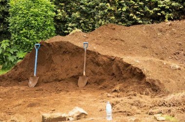 İki eski metal kürek büyük bir toprak yığınının yanında duruyor. Kazıcılar molada. Doğal ekolojik geleneksel çalışma konsepti