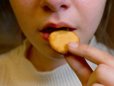 Bir genç yuvarlak bir bisküvi yer, ısırır ve ağzına yakın durur. Beslenme fırını ve sağlıklı konsept