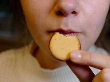 Bir genç yuvarlak bir bisküvi yer, ısırır ve ağzına yakın durur. Beslenme fırını ve sağlıklı konsept