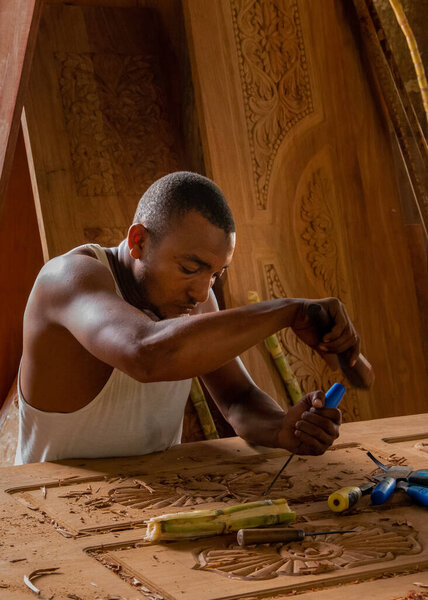 Stone Town, Zanzibar, Tanzania. 27 March 2018. Master woodcarver at work. Wood shavings, gouges and chisels on the workbench. Close up. master's hands at work