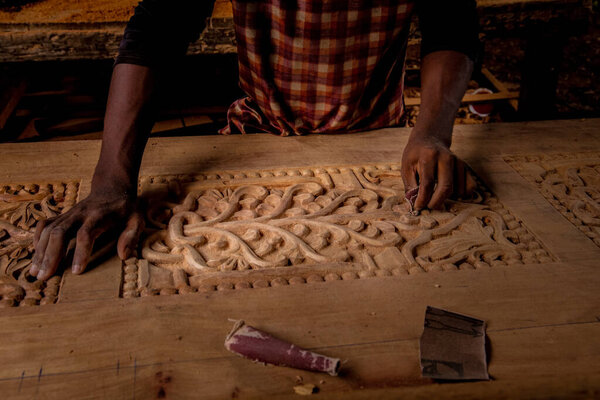 Stone Town, Zanzibar, Tanzania. 27 March 2018. Master woodcarver at work. Wood shavings, gouges and chisels on the workbench. Close up. master's hands at work