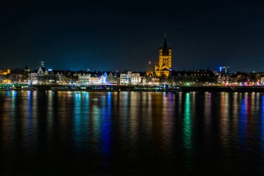 Köln, Almanya, 22 Şubat 2019. Parlak renkli ışıklarla aydınlatılan Köln gezisinin manzarası karşı kıyıdan gece.
