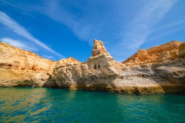 Garip şekiller kabartmalı kırmızı kayalık uçurum, Atlantik okyanus kıyısında güneş Portekiz Algarve 'i aydınlatıyor. Seyahat ve tatil konsepti