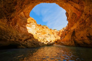 Portekiz Algarve 'nin ünlü mağaraları. Gökyüzünün görüntüsü kayadaki büyük bir delikten geçen bir kuyuya benziyor. Mavi gökyüzü ve kırmızı kayalar. Seyahat kavramı