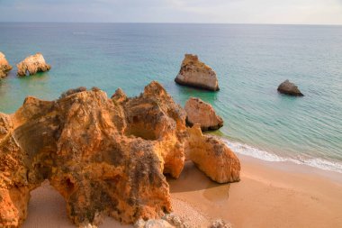 Garip şekiller kabartmalı kırmızı kayalık uçurum, Atlantik okyanus kıyısında güneş Portekiz Algarve 'i aydınlatıyor. Seyahat ve tatil konsepti