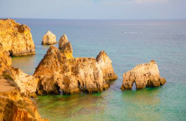 Garip şekiller kabartmalı kırmızı kayalık uçurum, Atlantik okyanus kıyısında güneş Portekiz Algarve 'i aydınlatıyor. Seyahat ve tatil konsepti