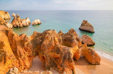 Garip şekiller kabartmalı kırmızı kayalık uçurum, Atlantik okyanus kıyısında güneş Portekiz Algarve 'i aydınlatıyor. Seyahat ve tatil konsepti