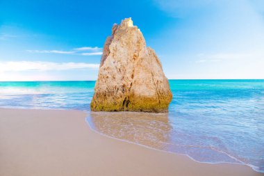 Garip şekiller. Okyanustaki dev kaya parçası. Gün batımı, mavi su arka planı. Okyanus doğası ve seyahat kavramı