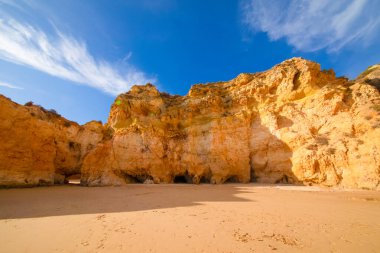 Garip şekiller kabartmalı kırmızı kayalık uçurum, Atlantik okyanus kıyısında güneş Portekiz Algarve 'i aydınlatıyor. Seyahat ve tatil konsepti