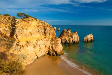 Garip şekiller kabartmalı kırmızı kayalık uçurum, Atlantik okyanus kıyısında güneş Portekiz Algarve 'i aydınlatıyor. Seyahat ve tatil konsepti