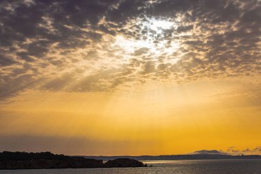 Atlantik Okyanusu üzerinde parlak ve resimli bir gün doğumu. Uzun güneş ışınları bulutların arasında parlıyor..