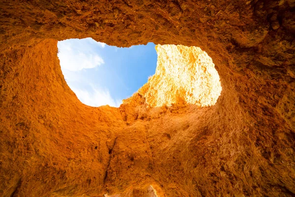 stock image famous caves of portugal algarve. the view of the sky as from a well through a huge hole in the stone. blue sky and red rocks. Travel concept