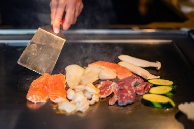 Şefin elleri teppanyaki yerine spatula ile. Sebze pişirmek et ve deniz ürünleri sıcak hibachi ızgara masasında. Geleneksel Japon mutfağı. Teppan gösterisi