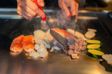 Şefin elleri teppanyaki yerine spatula ile. Sebze pişirmek et ve deniz ürünleri sıcak hibachi ızgara masasında. Geleneksel Japon mutfağı. Teppan gösterisi