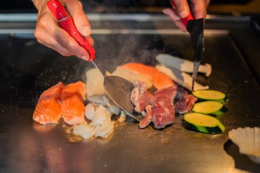 Şefin elleri teppanyaki yerine spatula ile. Sebze pişirmek et ve deniz ürünleri sıcak hibachi ızgara masasında. Geleneksel Japon mutfağı. Teppan gösterisi