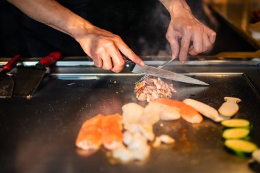Şefin elleri teppanyaki yerine spatula ile. Sebze pişirmek et ve deniz ürünleri sıcak hibachi ızgara masasında. Geleneksel Japon mutfağı. Teppan gösterisi